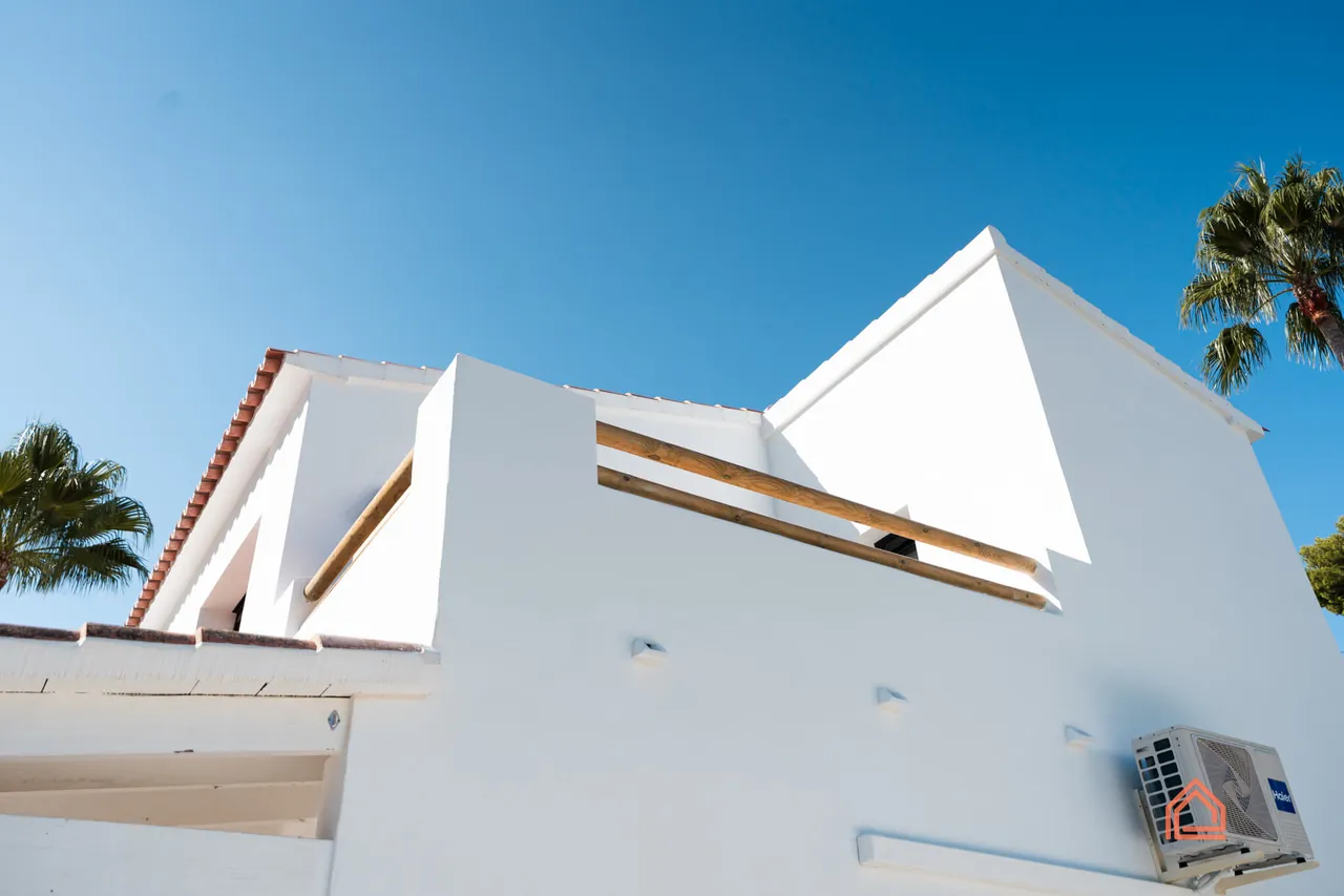 Low-angle view of a renovated white villa against a blue sky